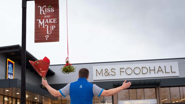 Aldi employee outside Skgness Aldi and M&S with a mistletoe that read "kiss and make up
