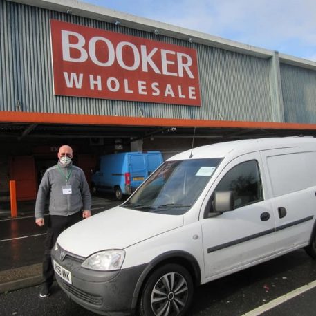 Man stood next to a white van in front of a Booker sign