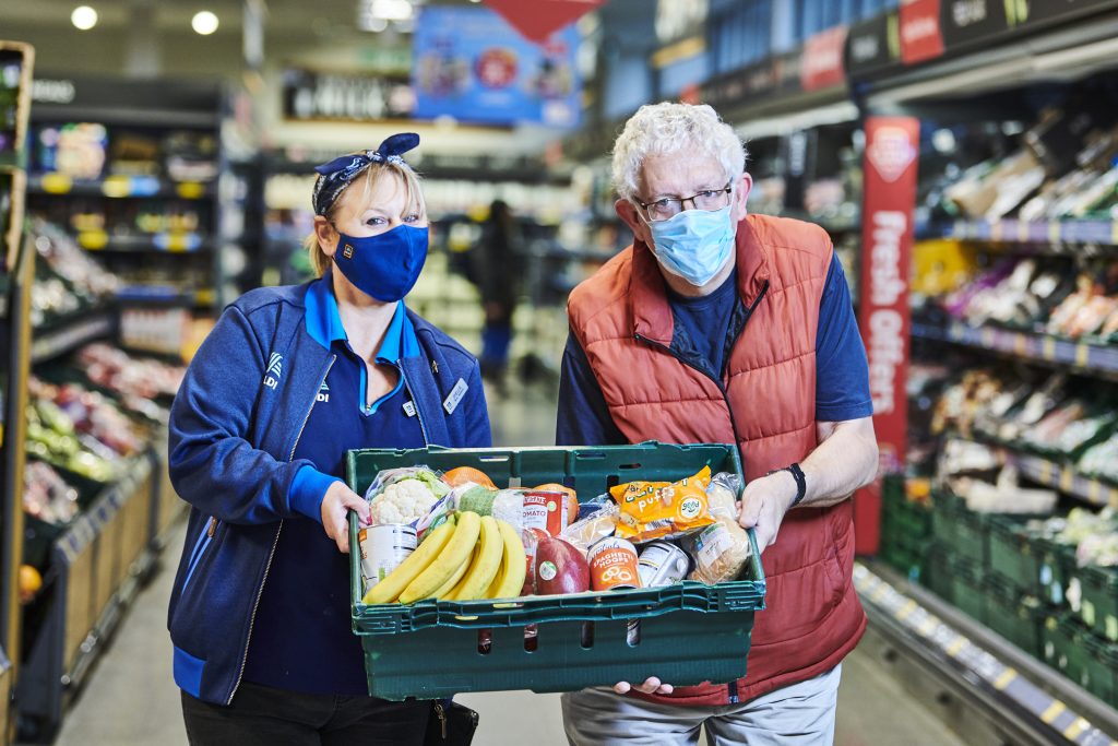 Aldi staff holding a box of donated produce.