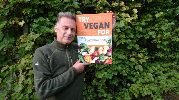Veganuary ambassador Chris Packham holds up a sign stating "try vegan for the environment".