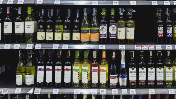 A supermarket shelf stacked with bottles of alcohol and wine.