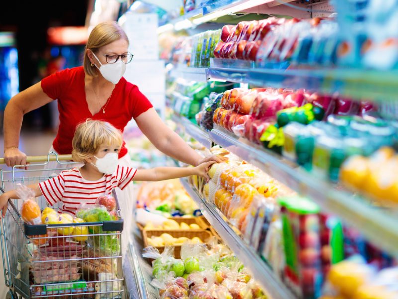 A mother and child wear masks while browsing a supermarket's chilled section.