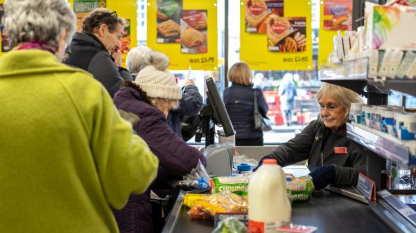 A supermarket worker scans items at the till.