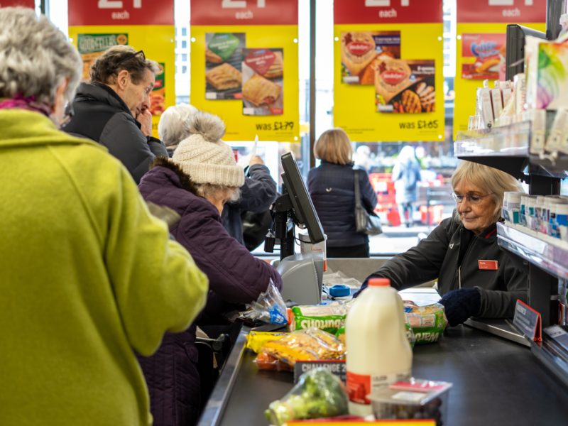A supermarket worker scans items at the till.