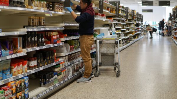 A supermarket worker re-stocks shelves.