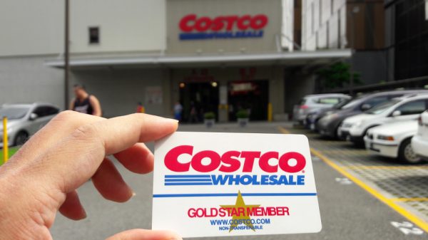 someone holding a Costco card in front of Costco