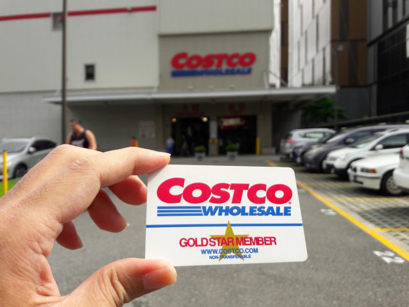 someone holding a Costco card in front of Costco