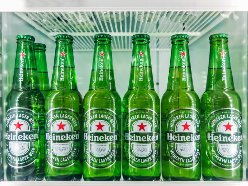 A row of Heineken beer bottles in a supermarket.