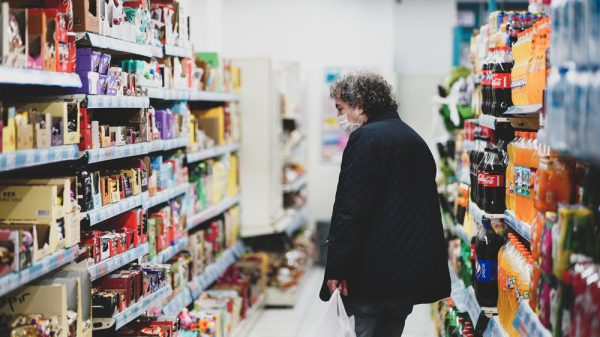 An older person walks the aisle of a convenience store.