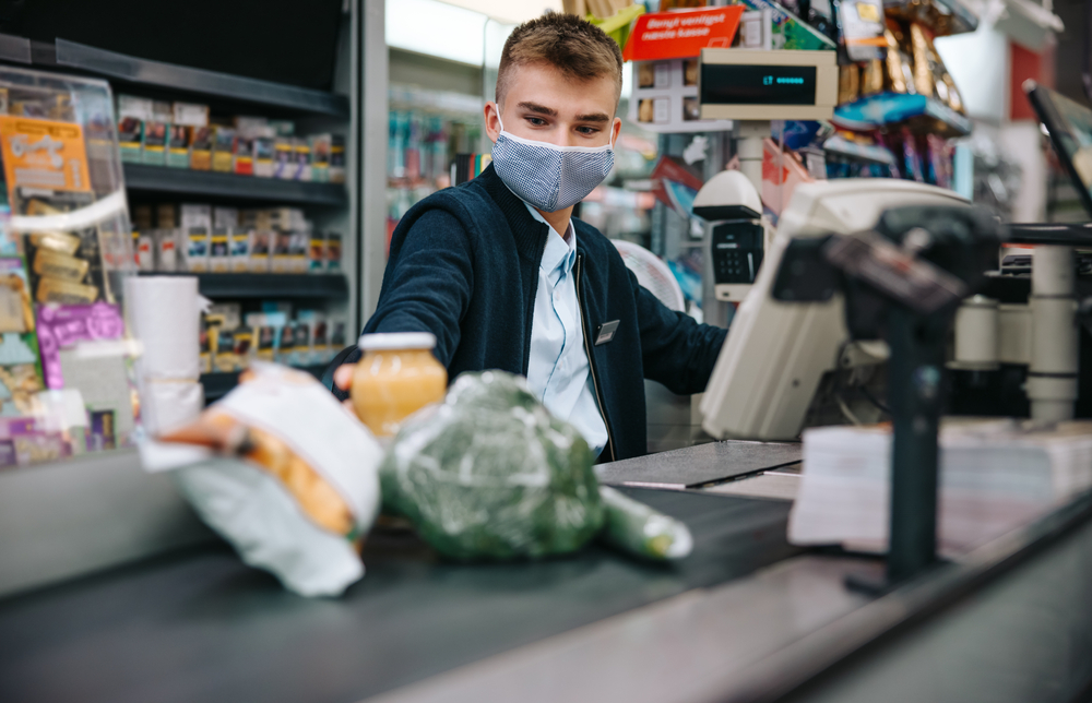 A supermarket worker wears a mask as they work at the tills.