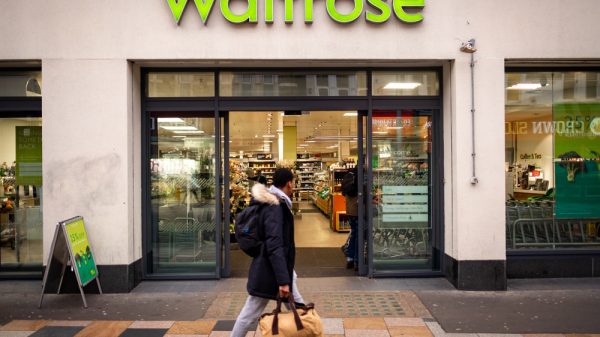 A person walks past a Waitrose storefront.