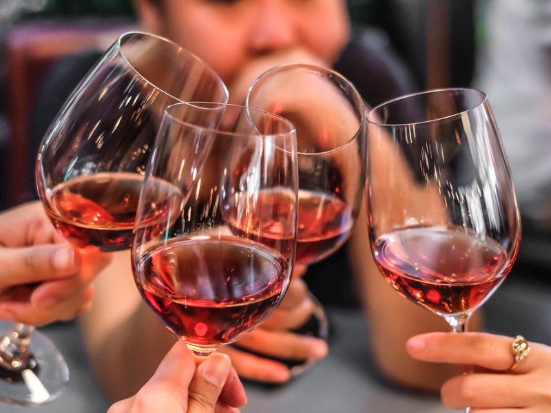 Four women cheers with a glass of wine.