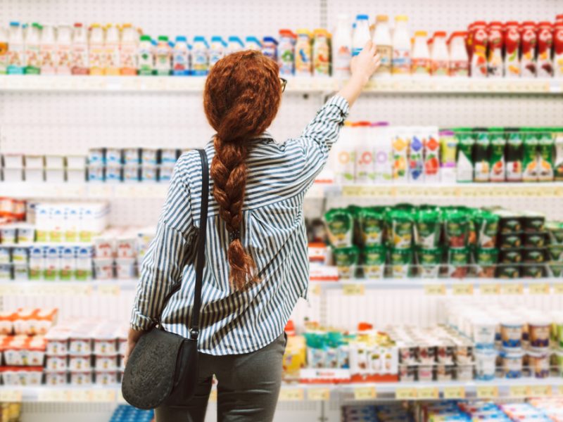 Person shopping in the yoghurt aisle in a supermarket.