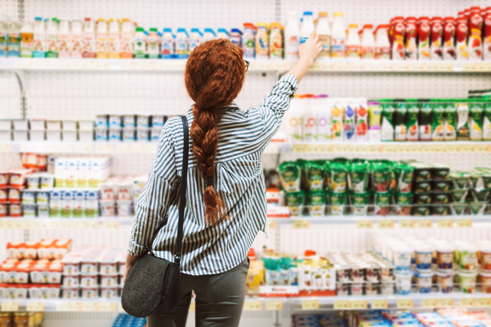 Person shopping in the yoghurt aisle in a supermarket.