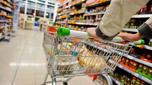 A person pushes a trolley down a supermarket aisle.