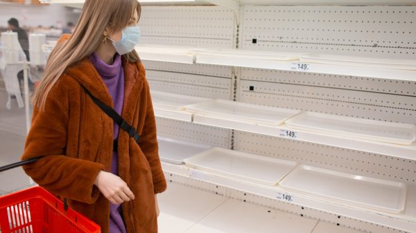 Customer in supermarket looking for food but shelves are empty