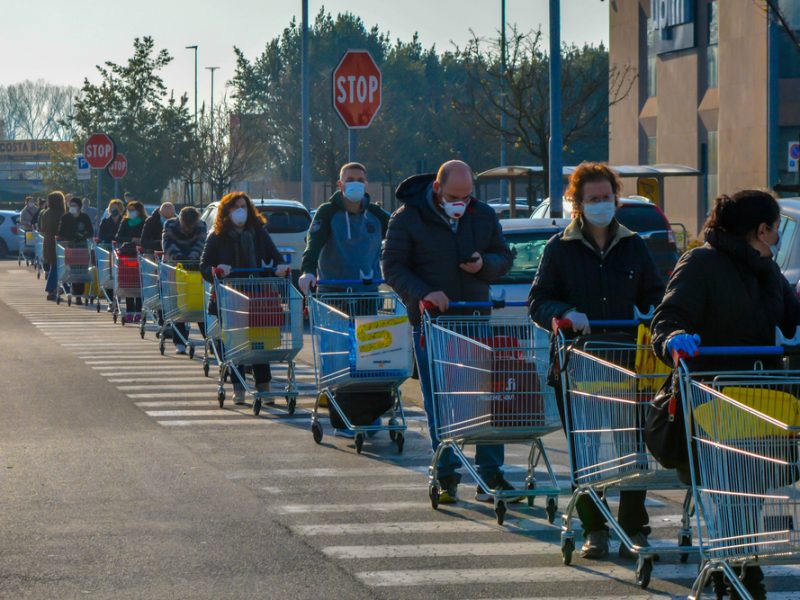 Customers queueing outside a grocery store