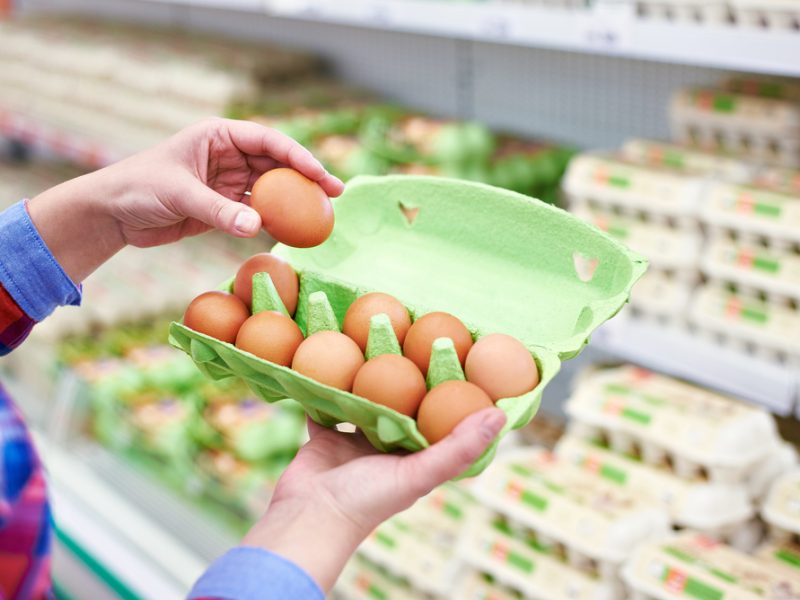 A hand picks out an egg from a carton in a supermarket.