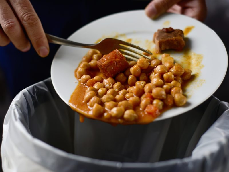 A pair of hands scrape a meal into a bin.