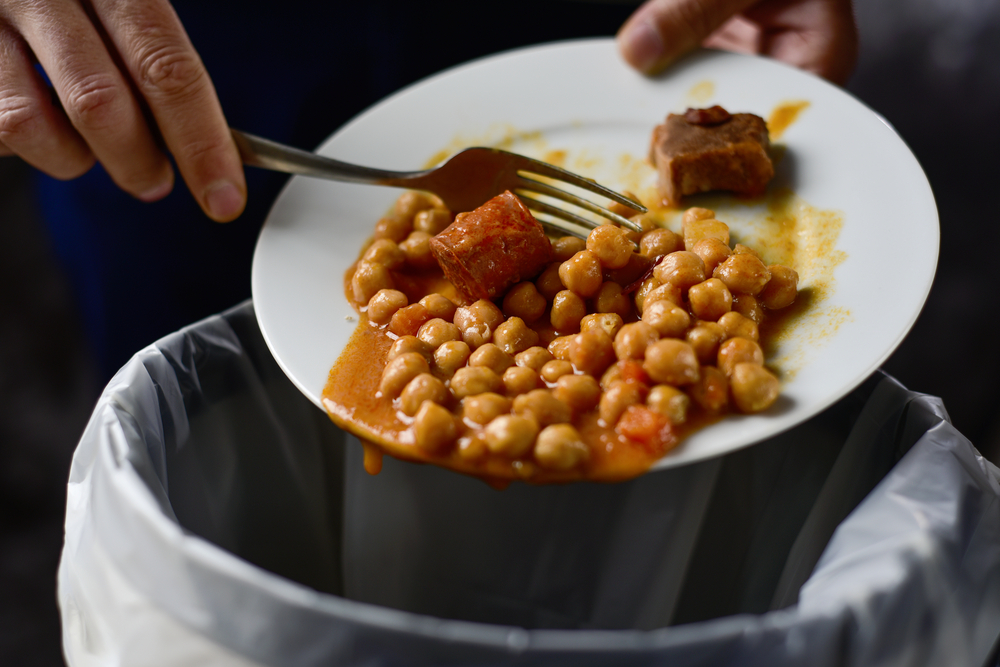 A pair of hands scrape a meal into a bin.