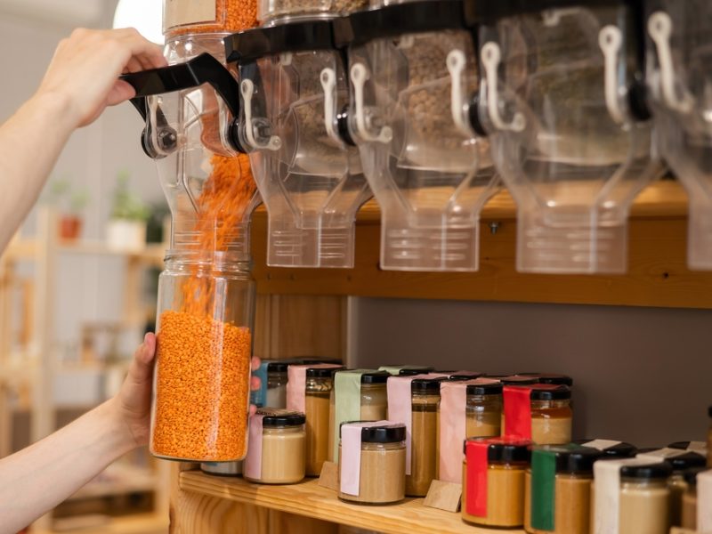 A dispenser pours lentils in a jar, within a refillable supermarket.