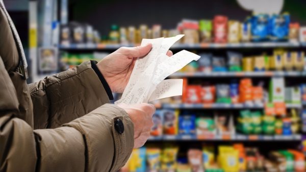 A pair of hands holds piling receipts in a supermarket.