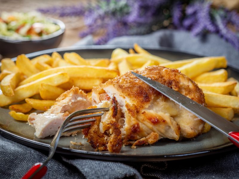 A fried chicken breast next to a portion of chips.