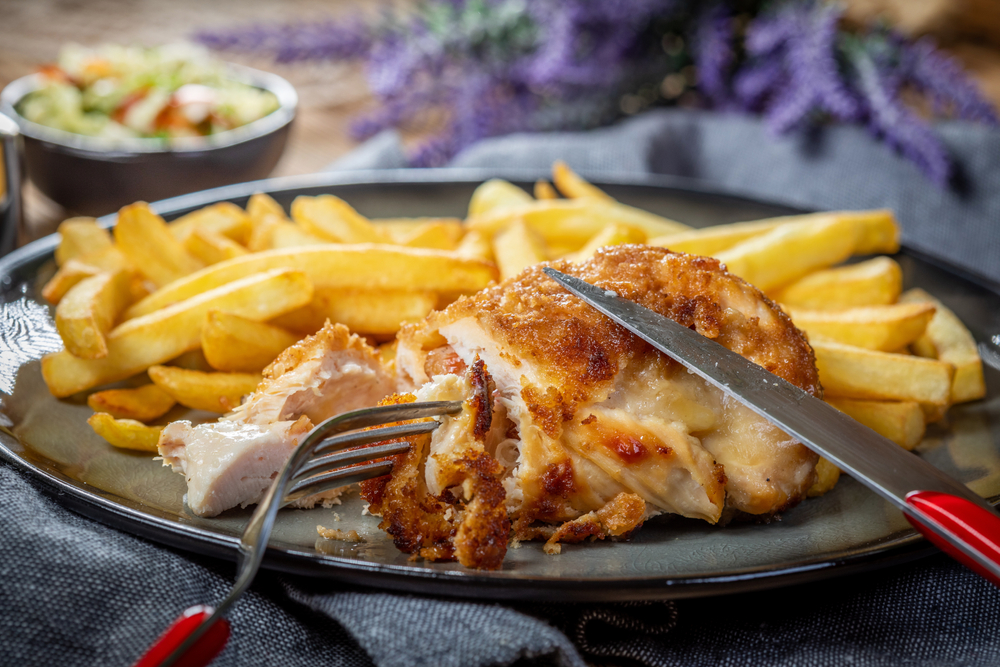 A fried chicken breast next to a portion of chips.