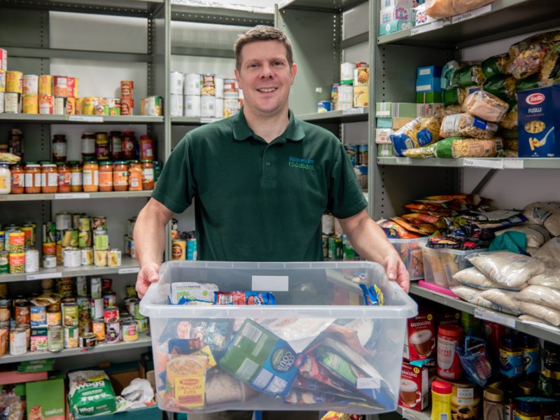 Food bank volunteer holding up box of goods