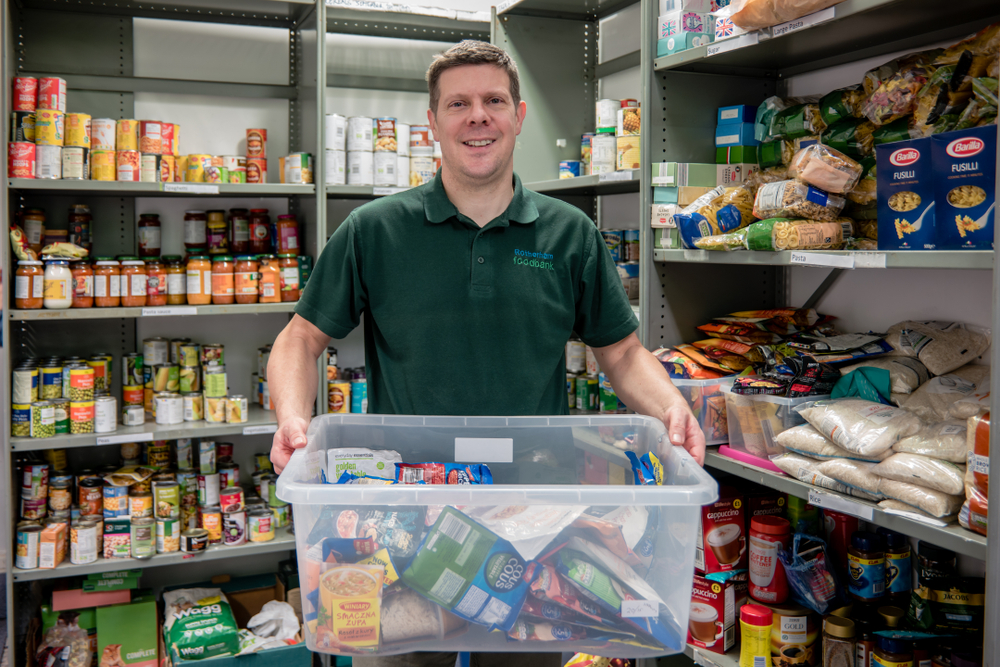 Food bank volunteer holding up box of goods