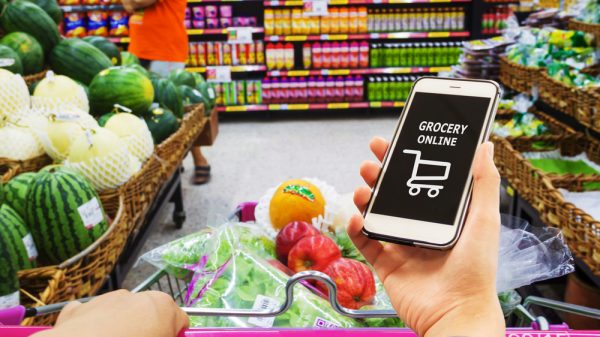Customer shopping in a supermarket but using online grocery app as well