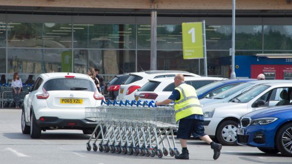 A Tesco worker pushing trolleys.