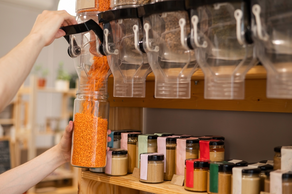 Hands refilling lentils at a store.
