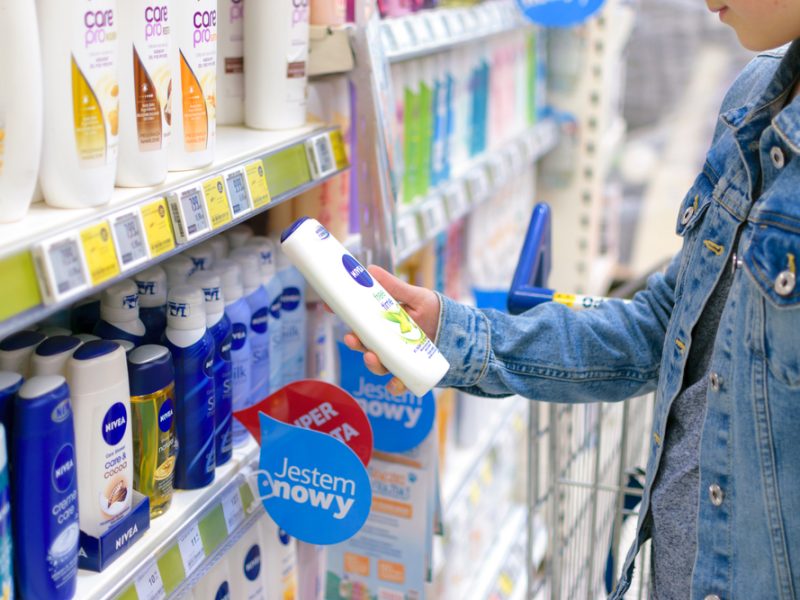 A hand grabs a branded cosmetic product in a supermarket.