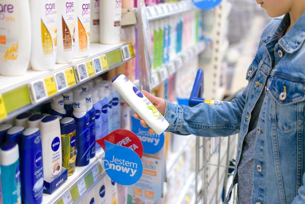 A hand grabs a branded cosmetic product in a supermarket.