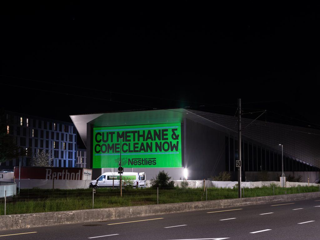 Climate campaigners have projected the slogans "Cut Methane" and "Come Clean Now" on to Nestlé's headquarters in Switzerland