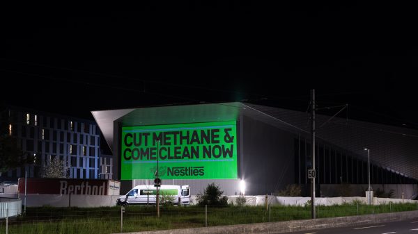 Climate campaigners have projected the slogans "Cut Methane" and "Come Clean Now" on to Nestlé's headquarters in Switzerland