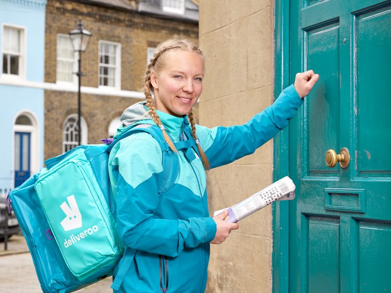 Deliveroo delivery person handing out newspapers
