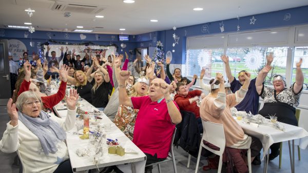 Aldi is spreading the festive cheer by bringing together local communities to donate Christmas lunches to low-income areas across the UK, here depicting people sitting down for a Christmas lunch