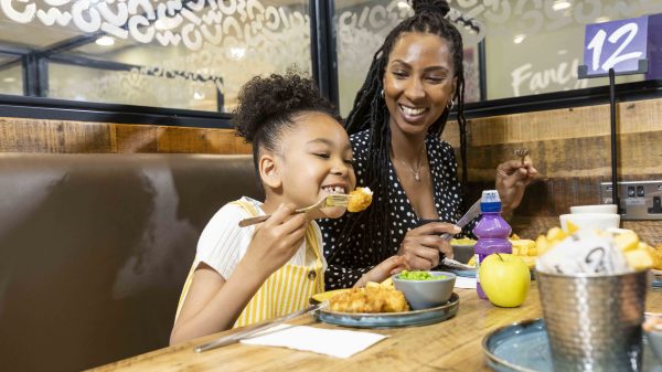 Morrisons is supporting families over the festive period with a new 'Kids Eat Free' initiative available at its cafés nationwide, here depicting a mother and a child eating under the new scheme
