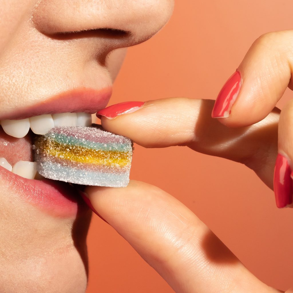 Co-op has agreed to a deal with nutritional gummy brand Nourished, to see the 3D-printed sweets hit the retailer's shelves, here depicting a woman placing a sweet into her mouth