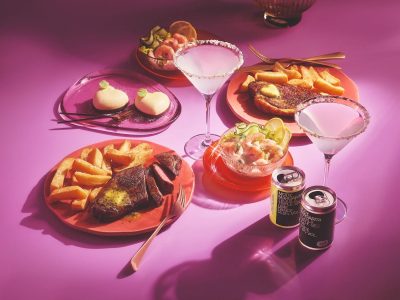 Depicting a Waitrose dine-in Valentine's range on a pink background showing two meals with tinned martini cocktails