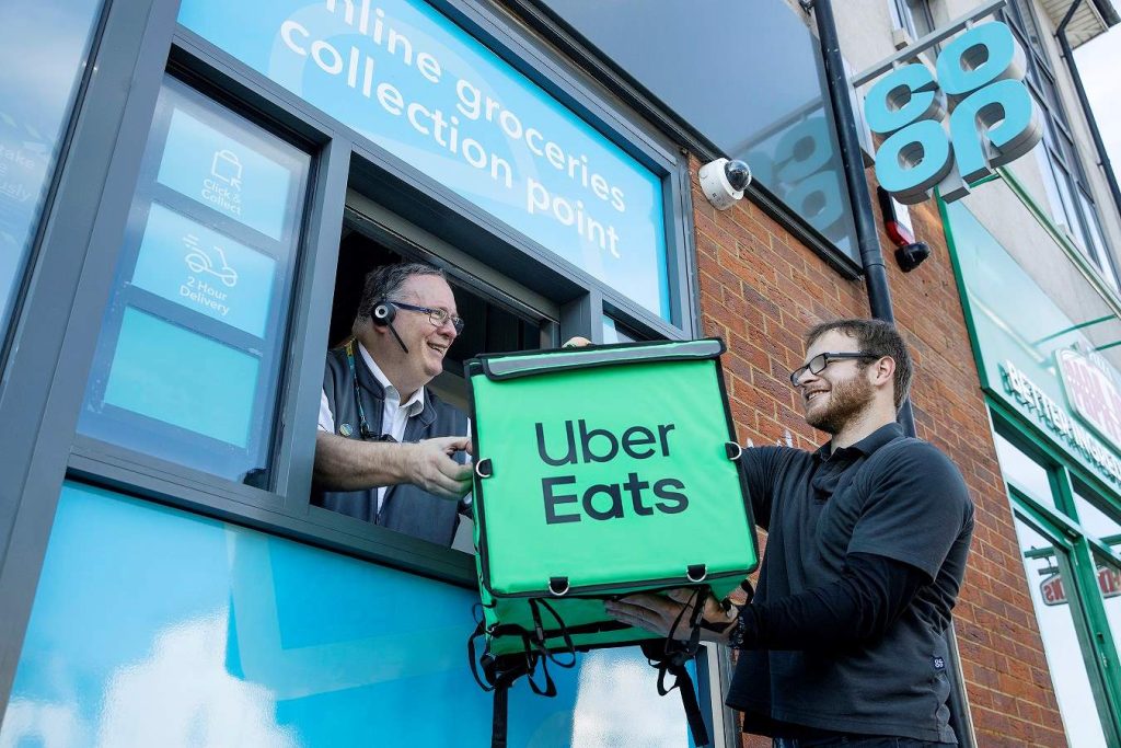 Here depicting an Uber Eat driver passing a branded delivery bag to a Co-op staff member