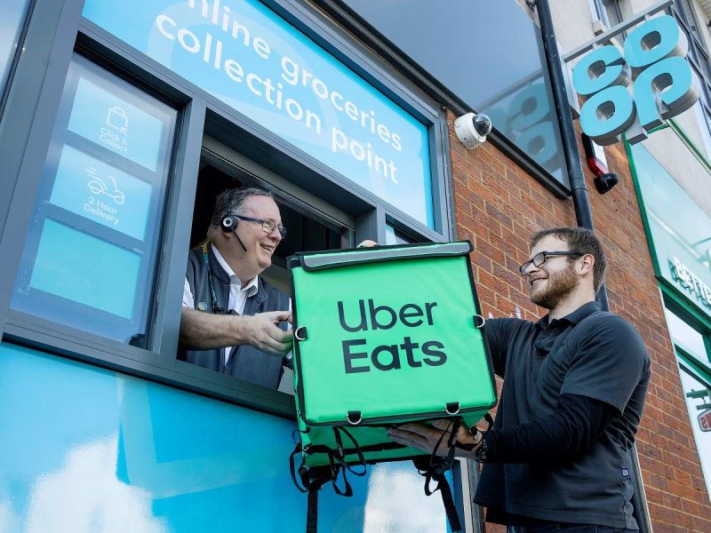 Here depicting an Uber Eat driver passing a branded delivery bag to a Co-op staff member