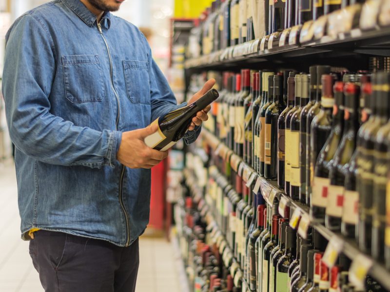 Here depicting a man looking at a bottle of alcohol on a shelf